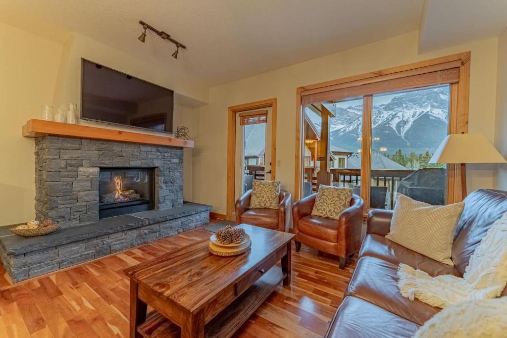 a living room with a couch and a fireplace at Rundle Range Retreat Lux Mtn View Condo near dt in Canmore