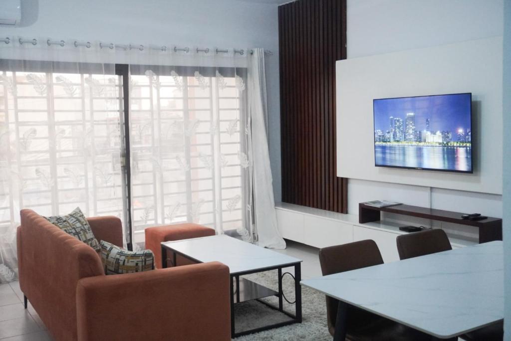 a living room with a couch and a tv at SEJOURABIDJAN - Residences Cocody Angré in Abidjan
