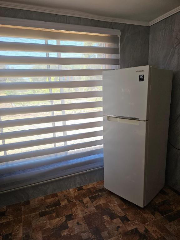 a white refrigerator in a room with a window at Ribera del Ancoa in Llepu