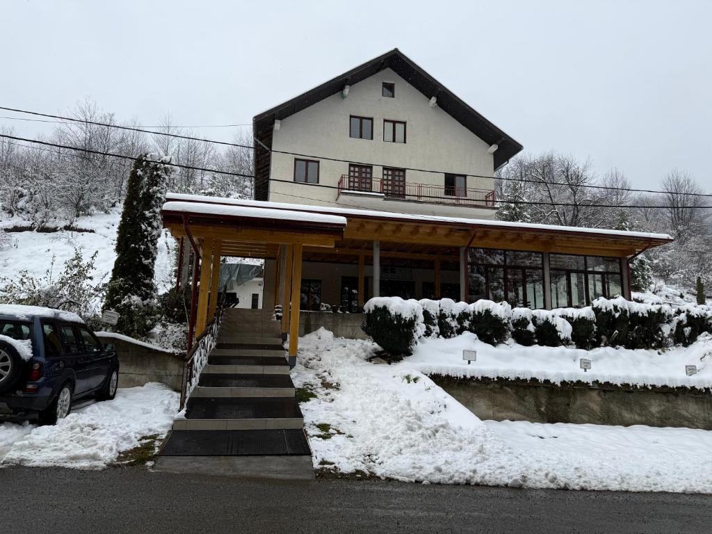 a house with a car parked in the snow at Apartments and Rooms Vicko in Brzeće