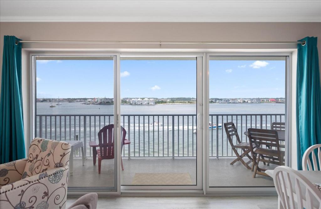a living room with a balcony with a view of the water at Amazing Bay view from this Assateague House Condo in Ocean City