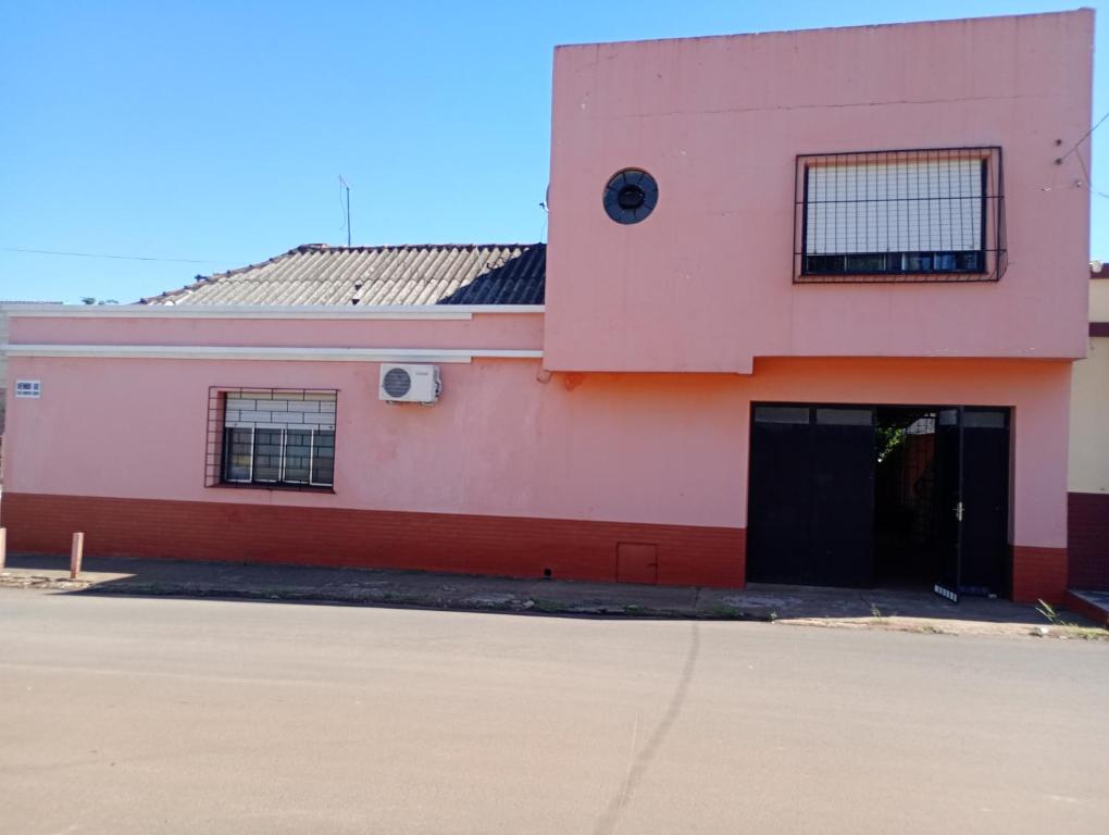 a pink and red building with a garage at Posada domiciliar DB in São Gabriel