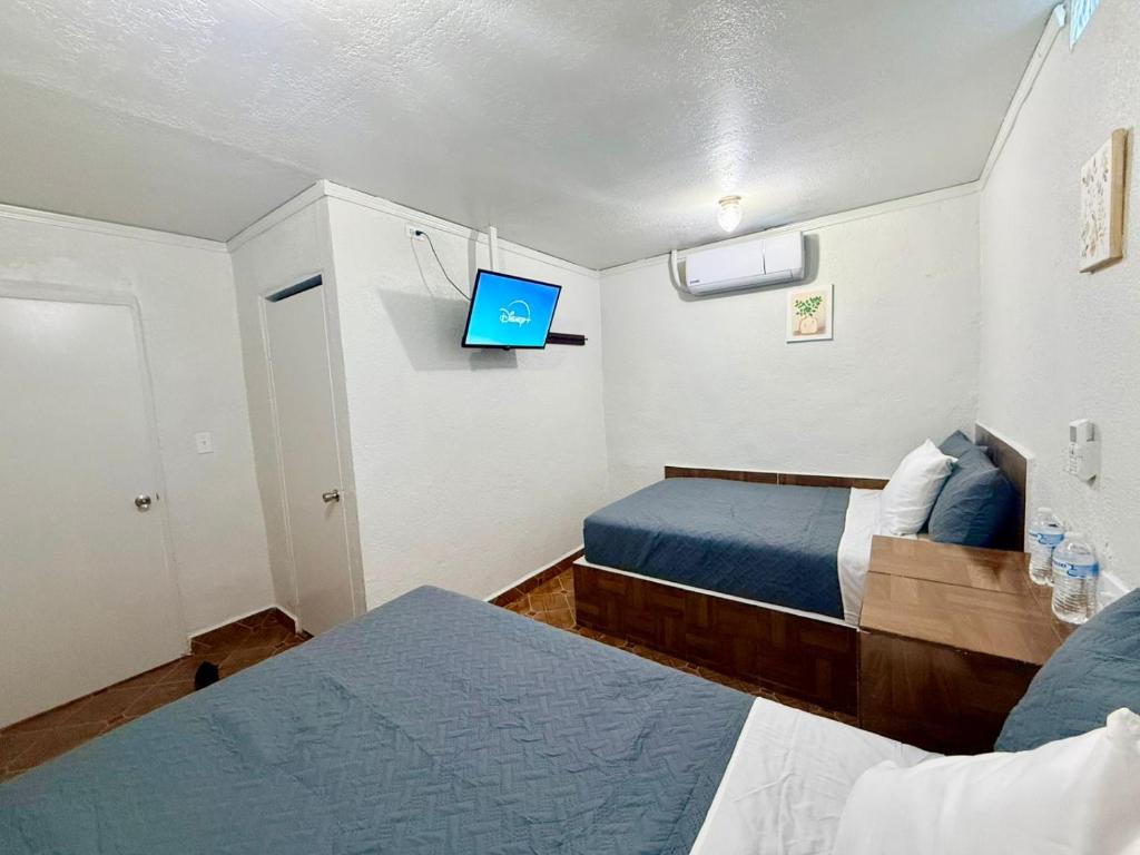 a bedroom with two beds and a tv on the wall at Comod Inn in Manuel F. Martínez