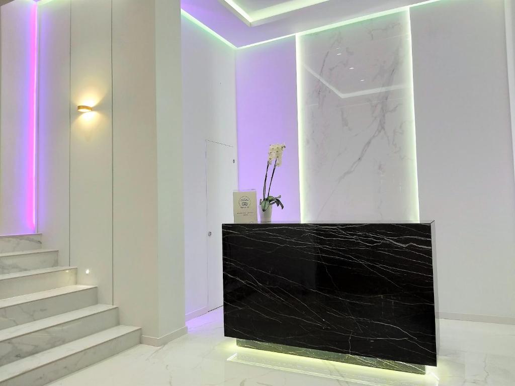 Un vestíbulo con un mostrador negro e iluminación violeta. en Akrogiali Exclusive Hotel (Adults Only), en Polychrono