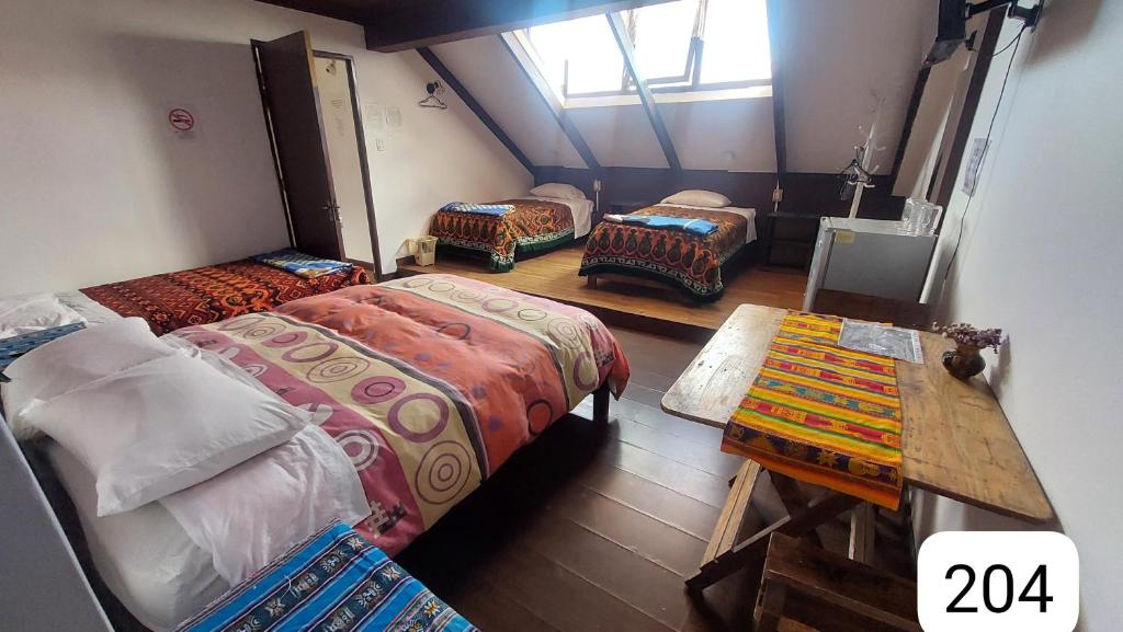 une chambre mansardée avec trois lits et une table dans l'établissement Centro Cultural Distrito, à Sucre