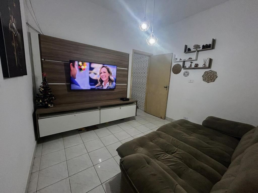 ein Wohnzimmer mit Sofa und Flachbildfernseher in der Unterkunft Casa aconchegante na Vila Tupi - Perto da Praia in Praia Grande
