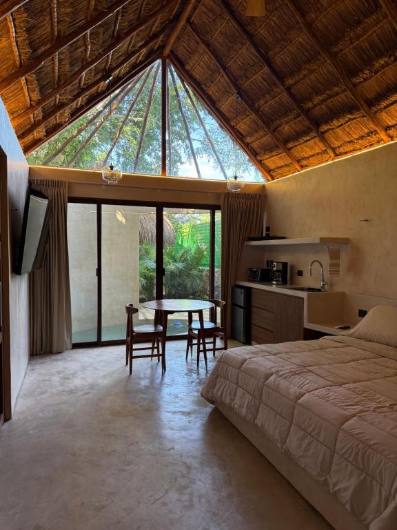 a bedroom with a bed and a table with chairs at Aldea 58, cabañas de lujo con piscina en Merida centro in Azcorra