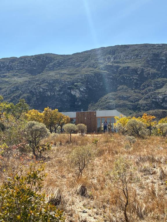a building in a field with a mountain in the background at Chalé Corumbau - Lapinha da Serra in Santana do Riacho