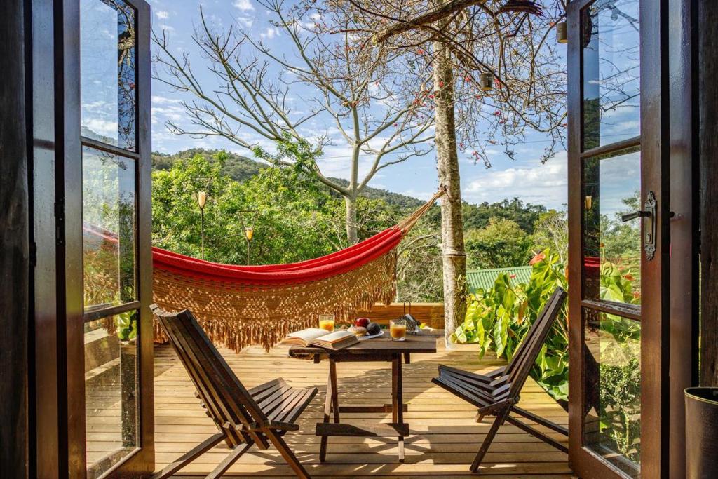 een veranda met een hangmat en een tafel en twee stoelen bij Pousada DVeras in Garopaba