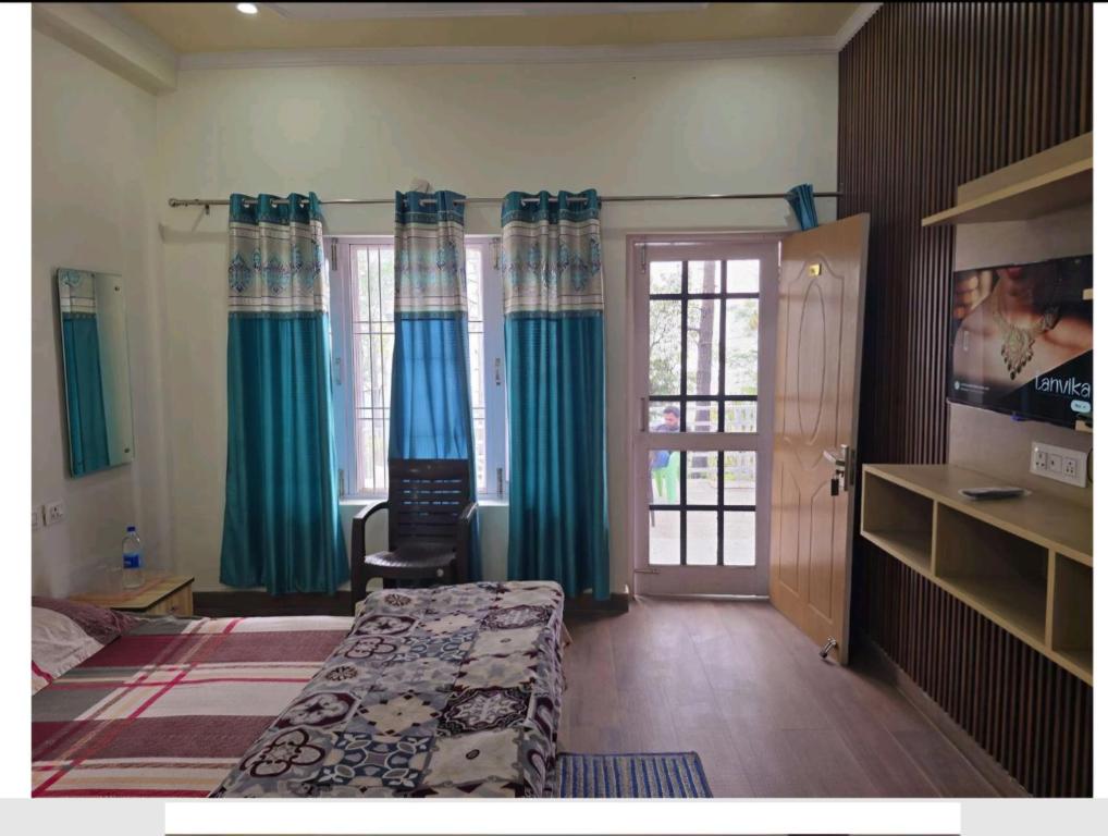 Schlafzimmer mit einem Bett, blauen Vorhängen und einer Tür in der Unterkunft Rudrashray Paradise Mussorie in Masuri