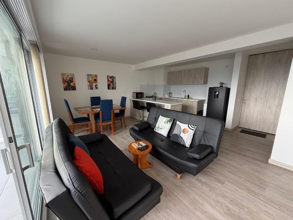 Una sala de estar con un sofá negro y una cocina. en Amplio y Suntuoso - estrato 6, en Manizales