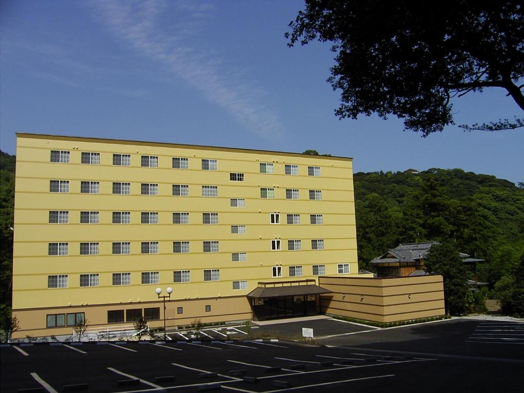 un edificio amarillo con un estacionamiento delante de él en Atami Hotel Paipuno Kemuri en Atami