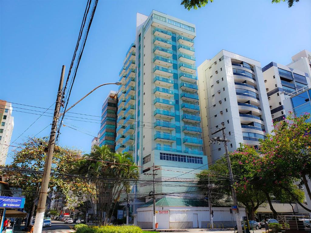 un edificio alto azul y blanco en una calle de la ciudad en Triângulo Apart Hotel, en Vitória