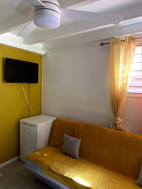 a living room with a couch and a tv at Le Tomaflo in Le Marin