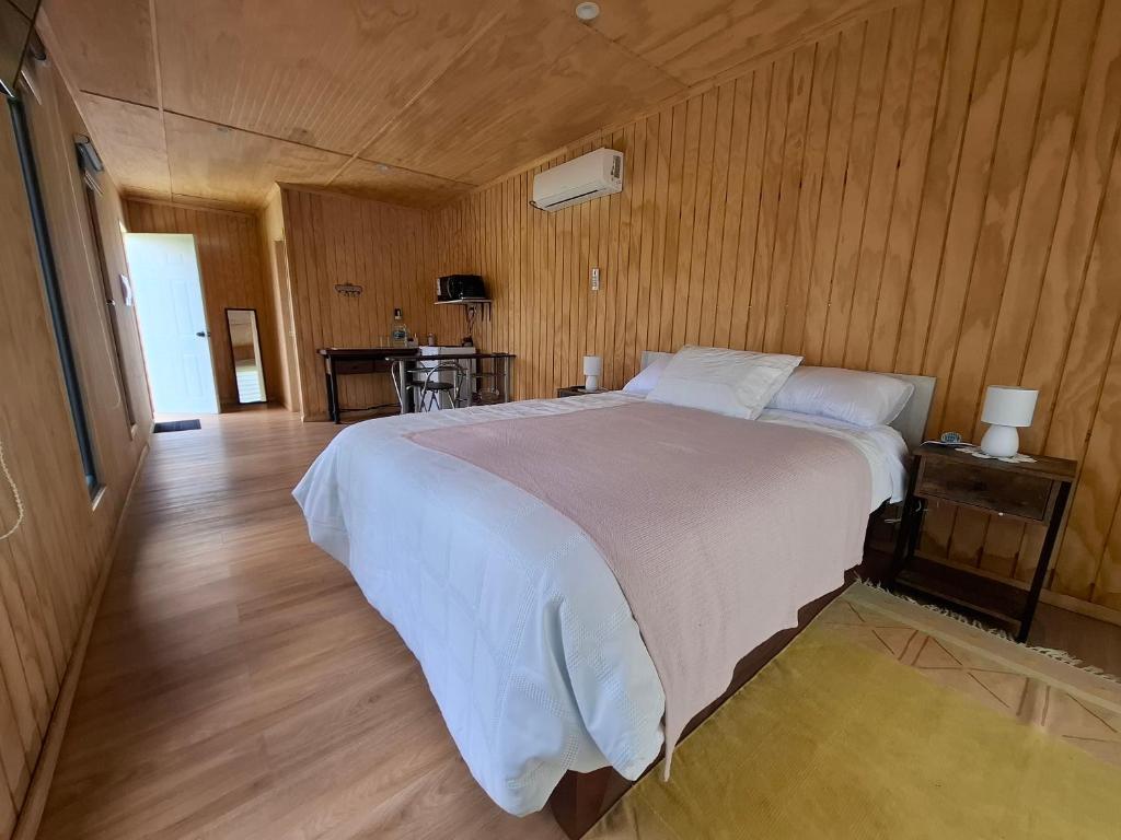 a bedroom with a large white bed and wooden walls at Tiny 2 in Los Ángeles