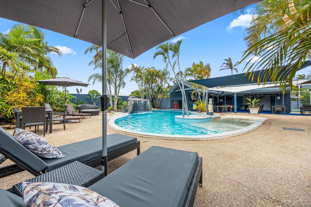 una piscina con sillas y sombrilla en Grange Resort Hervey Bay, en Hervey Bay