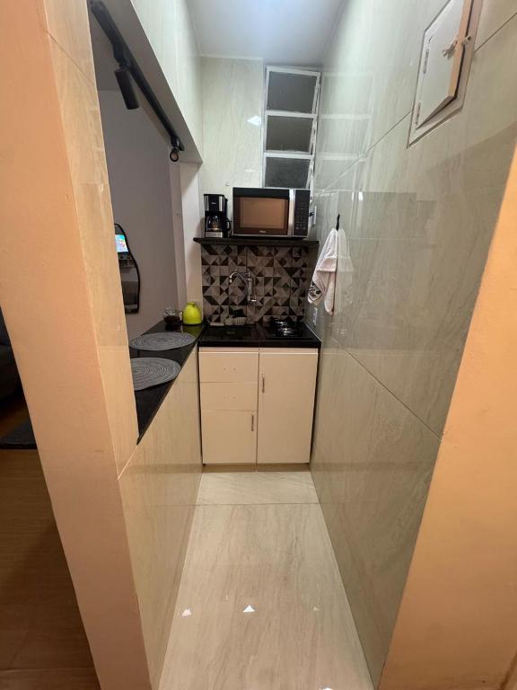 a small kitchen with white cabinets and a stove at Kitnet Petrópolis in Petrópolis