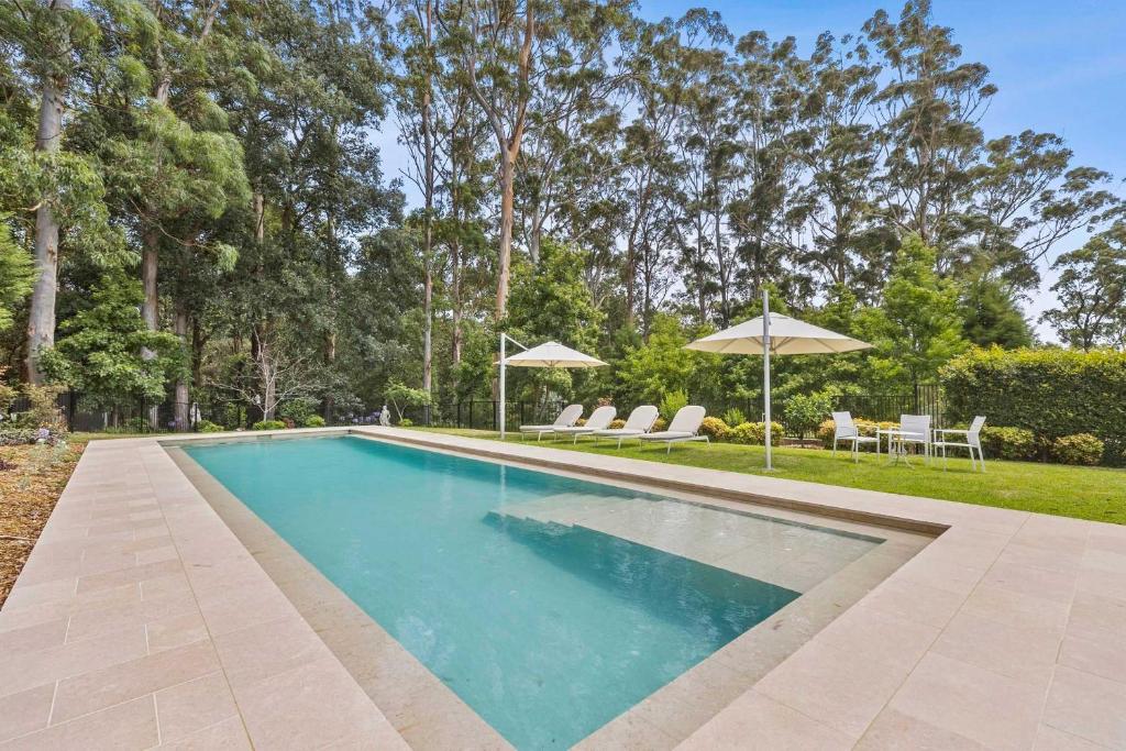a swimming pool with chairs and umbrellas at Tarragal by Coast Hosting in Terrigal