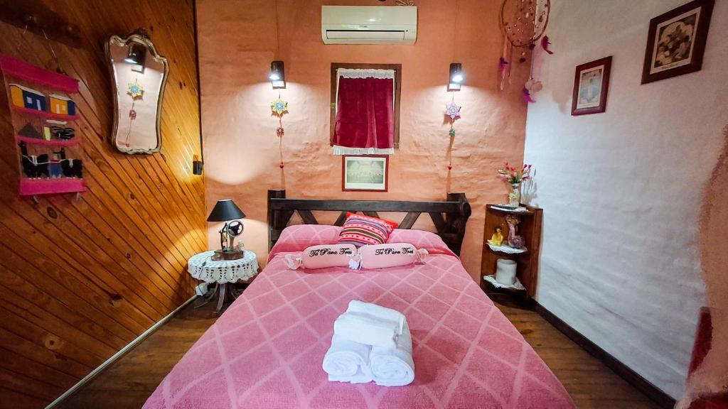 Un dormitorio con una cama rosa con toallas. en Cabaña 'Te para Tres' Merlo San Luis, en Merlo