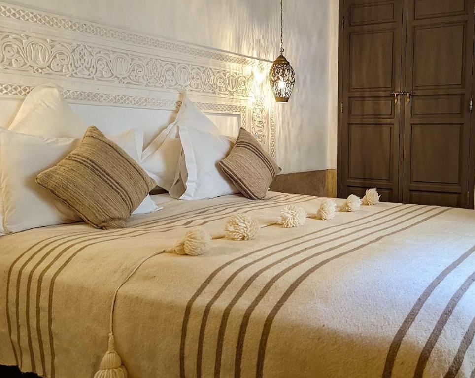 um quarto com uma cama grande com travesseiros brancos em Maison al Andalus em Essaouira