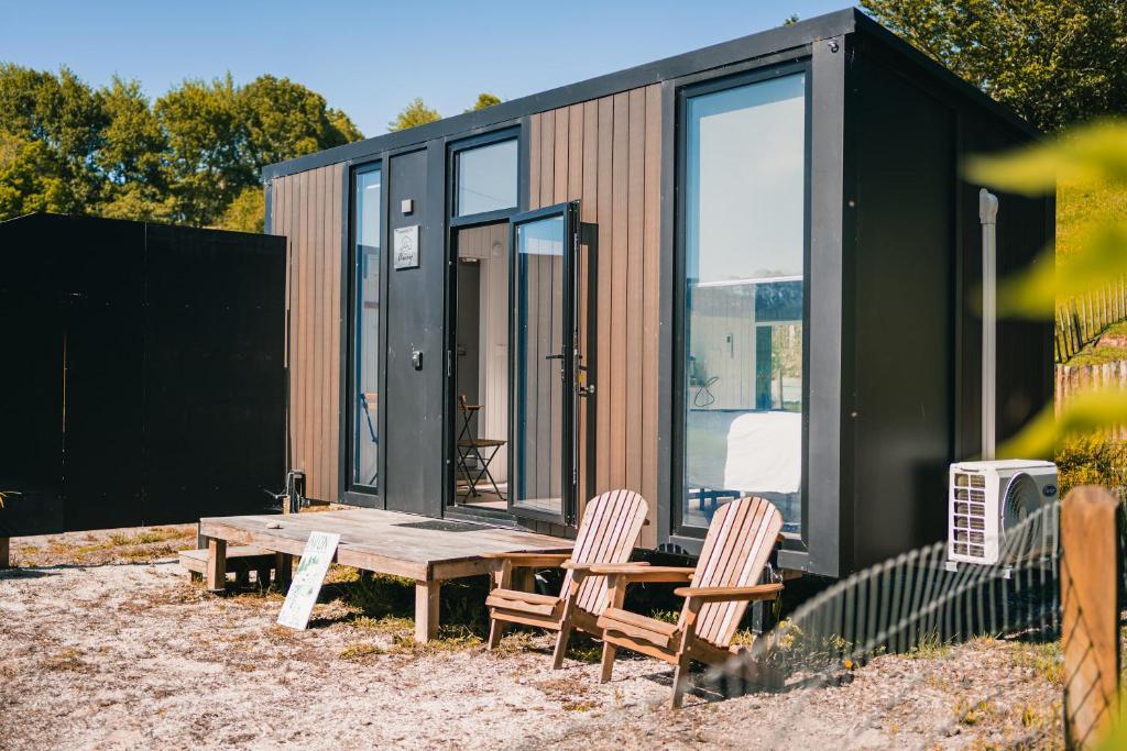 een klein huisje met twee stoelen en een houten tafel bij Avon Cabin by Tiny Away in Huiroa