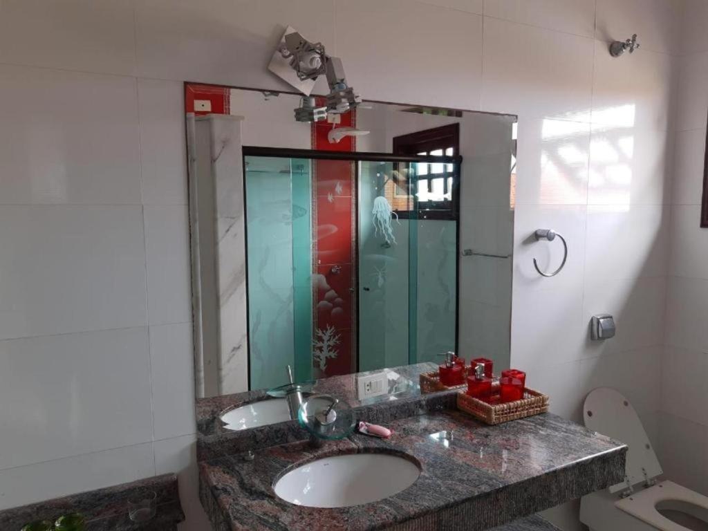 une salle de bain avec un lavabo et un grand miroir dans l'établissement Pousada Preziosa Beach Itanhaém, à Itanhaém