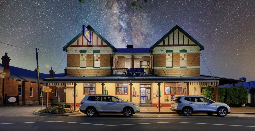 due auto parcheggiate in un parcheggio di fronte a un edificio di Maclean Hotel a Maclean