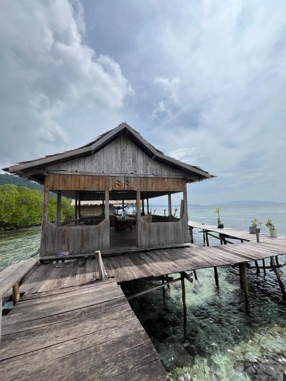 a wooden pier with a building on the water at Korbekwan Homestay in Besir