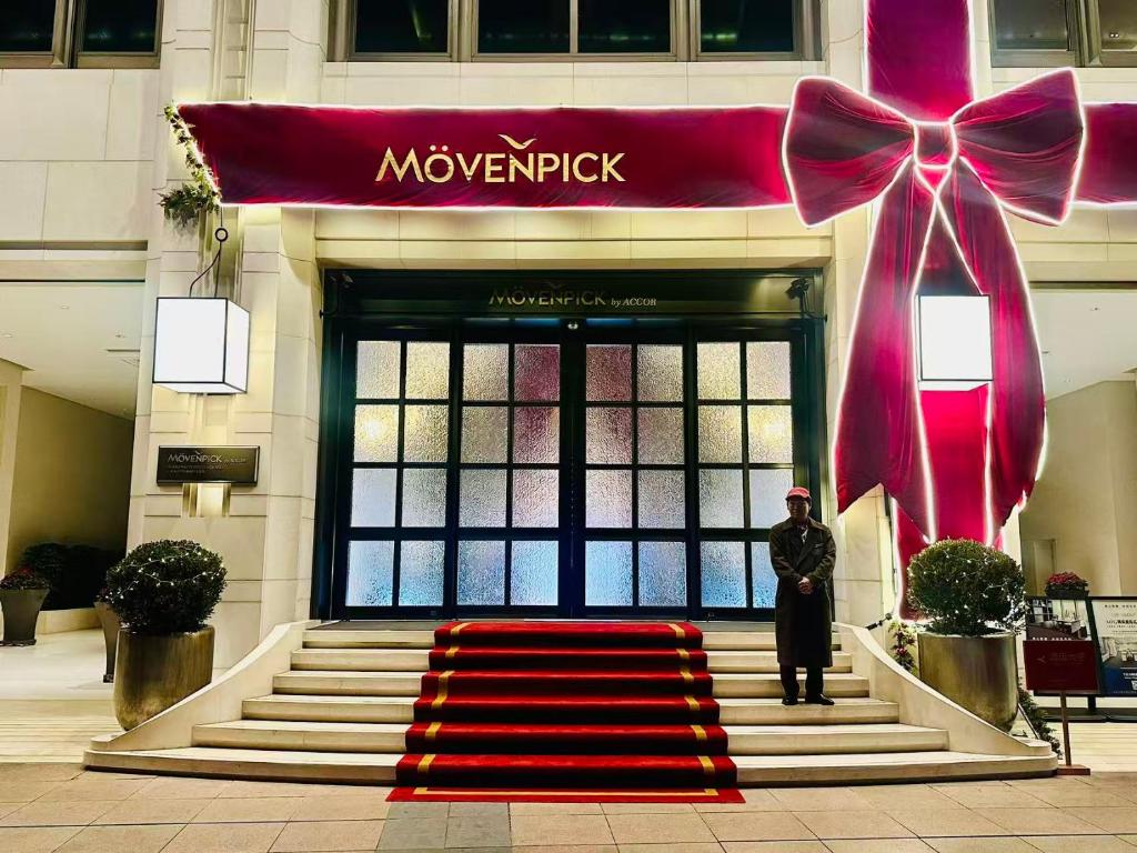 um tapete vermelho em frente a um prédio com um grande laço em Mövenpick by Accor Shanghai People's Square em Xangai