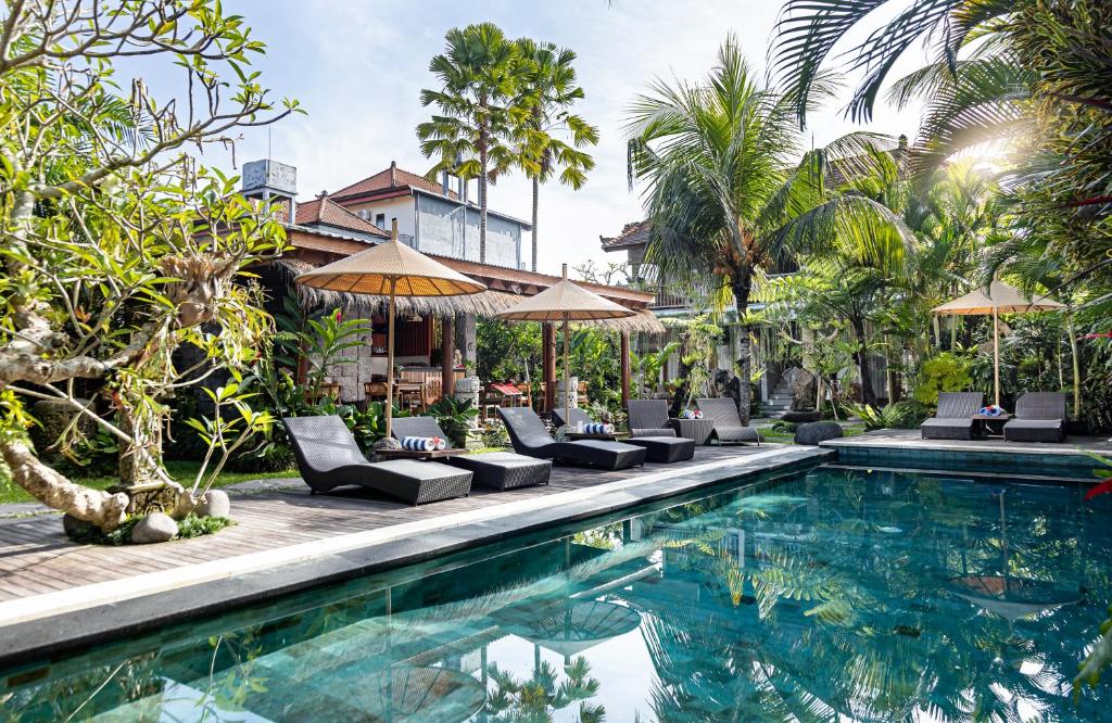 een zwembad op een resort met stoelen en parasols bij The Runik Ubud in Ubud