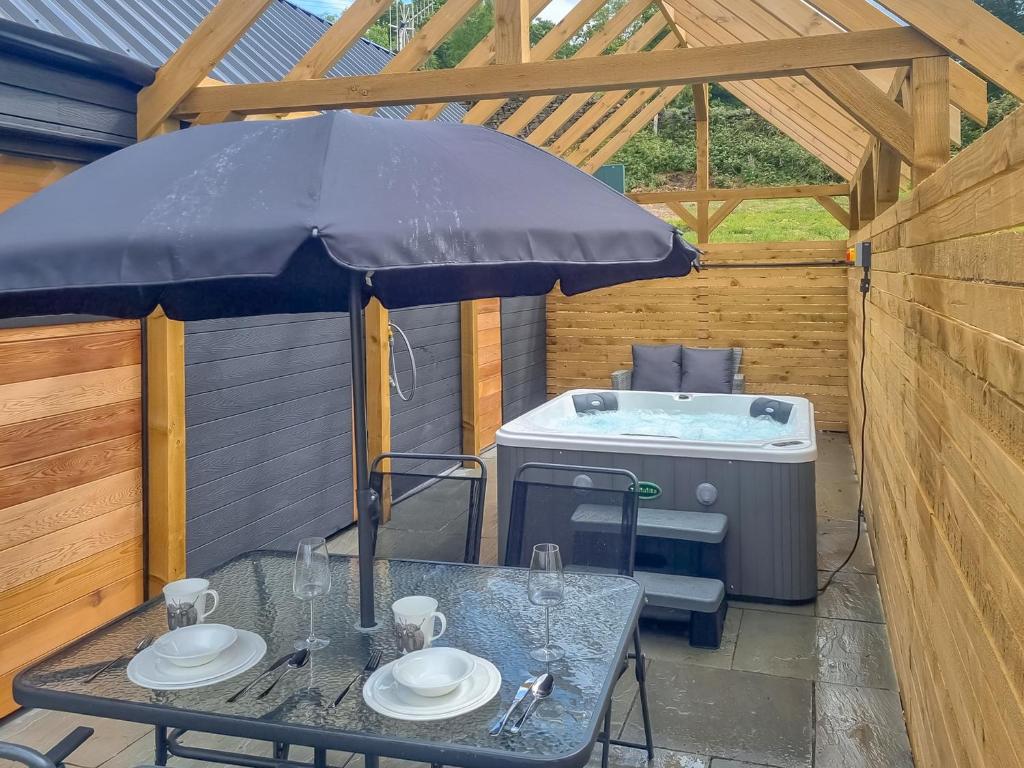a picnic table with an umbrella and a grill at Tyan - Uk49354 in Gatebeck