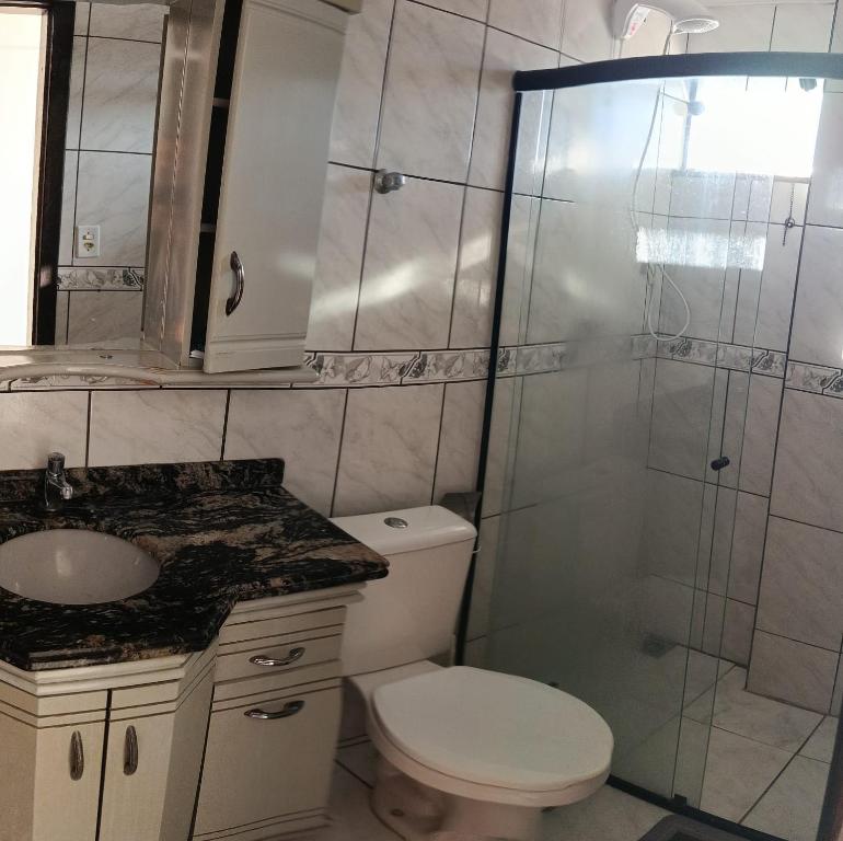 een badkamer met een douche, een toilet en een wastafel bij Pensionato Marlu I in Balneário Camboriú