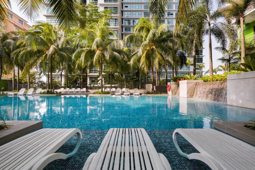 a swimming pool with palm trees in a building at Acappella Suite Hotel, Shah Alam in Shah Alam