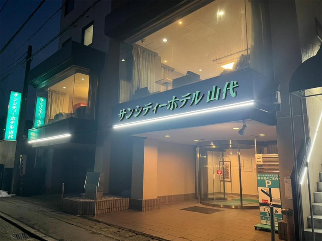 ein Gebäude mit einem Neonschild an der Seite in der Unterkunft サンシティーホテル山代 in Kaga
