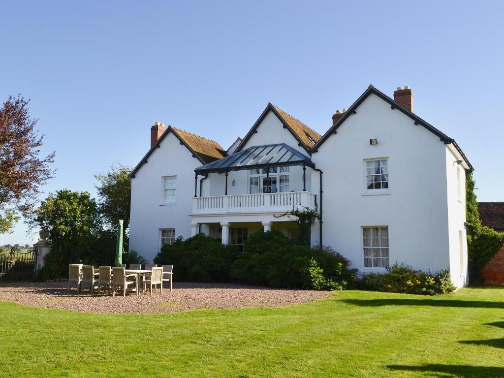 a white house with tables and chairs in front of it at Lees Farm Apartment in Walcot
