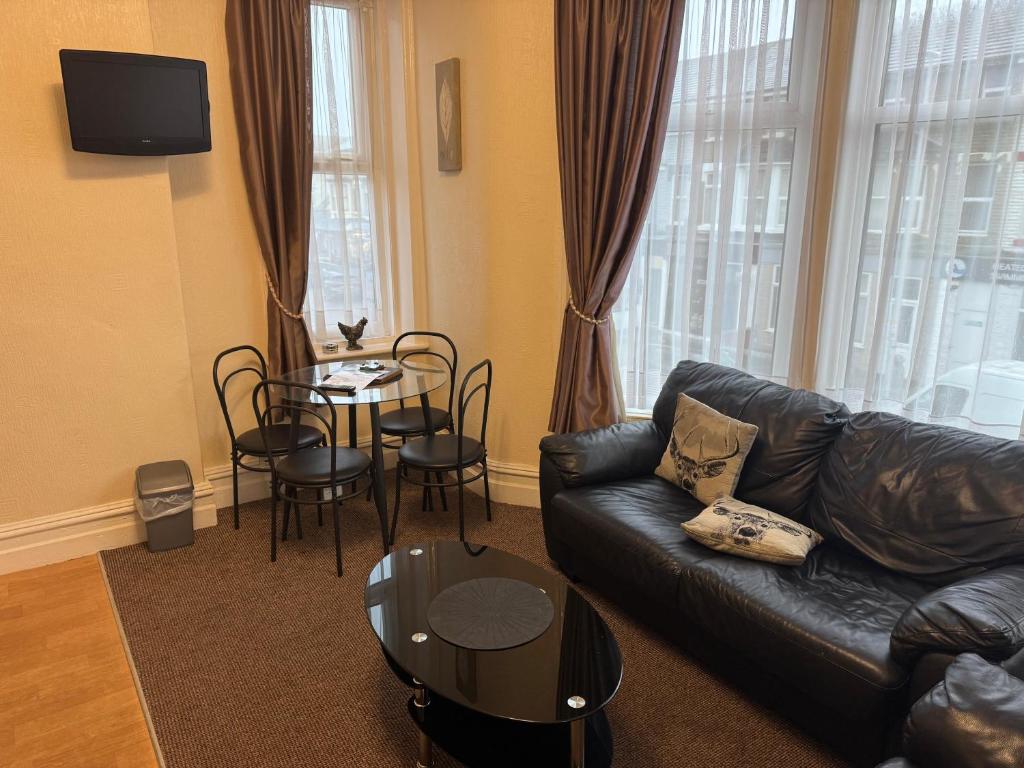 een woonkamer met een leren bank en een tafel bij Woodfield Lodge Apartments in Blackpool