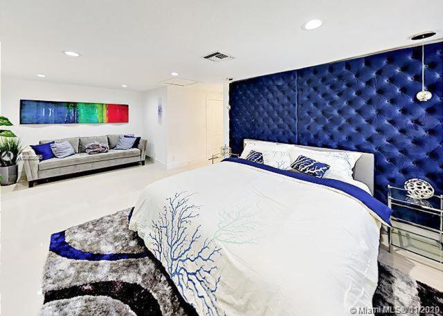 a bedroom with a large bed with a blue headboard at The Chill Crib in Fort Lauderdale