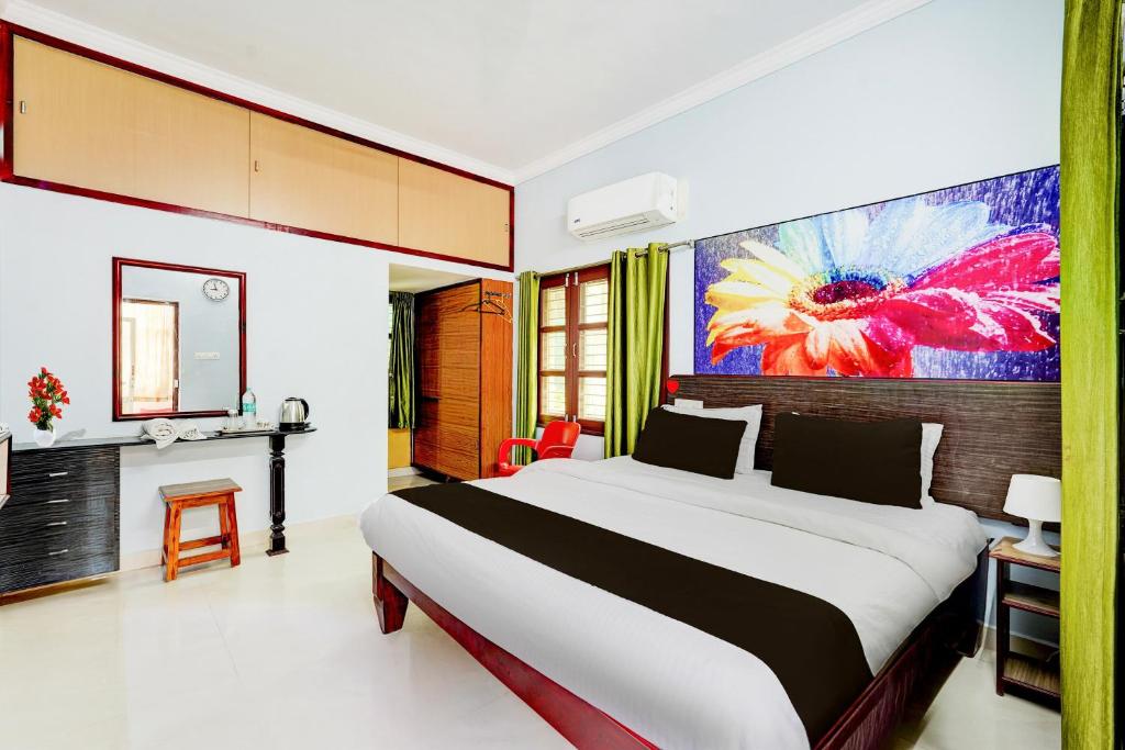 a bedroom with a large bed and a painting on the wall at Super Hotel O Chittoor Railway Station Formerly Four Oaks in Chittoor