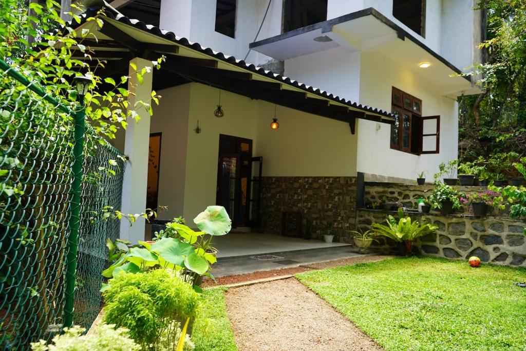 een wit huis met een hek en een tuin bij Villa Hideout in Unawatuna