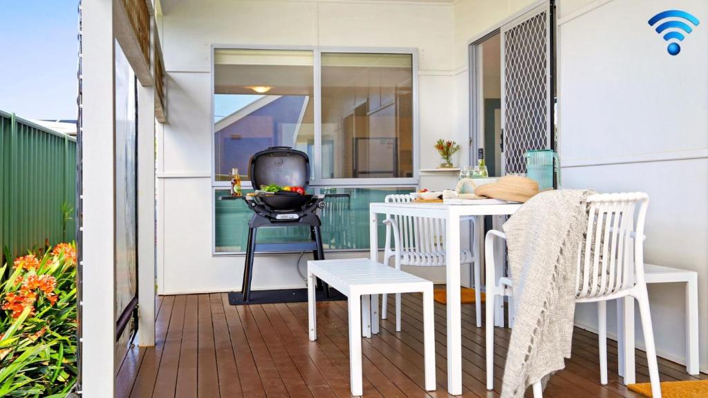 een klein balkon met een witte tafel en stoelen bij Rockpool Retreat in Currarong