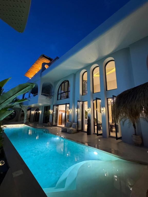 a swimming pool in front of a house at night at Villa Shugo Tenshi in Badung