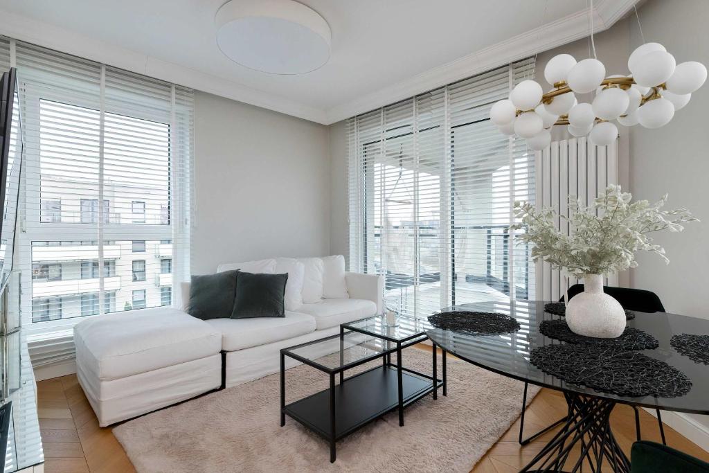a living room with a white couch and a glass table at Elegant Apartment with Parking Space and Balcony by Noclegi Renters in Gdynia