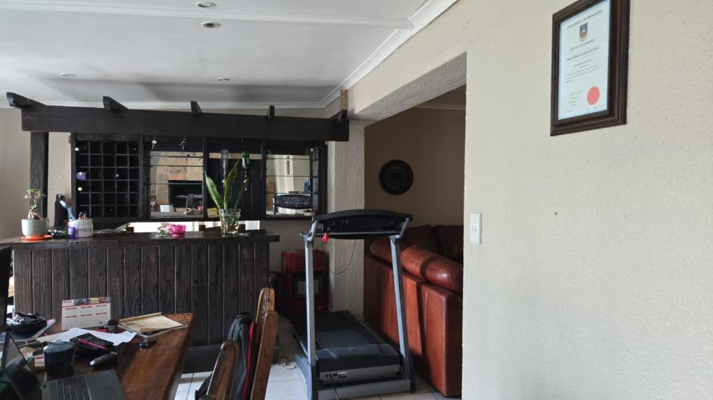 een woonkamer met een loopband naast een tafel bij Nyati in Cape Town