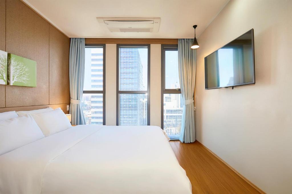 a bedroom with a white bed and a large window at Hotel POCO Seongsu in Seoul