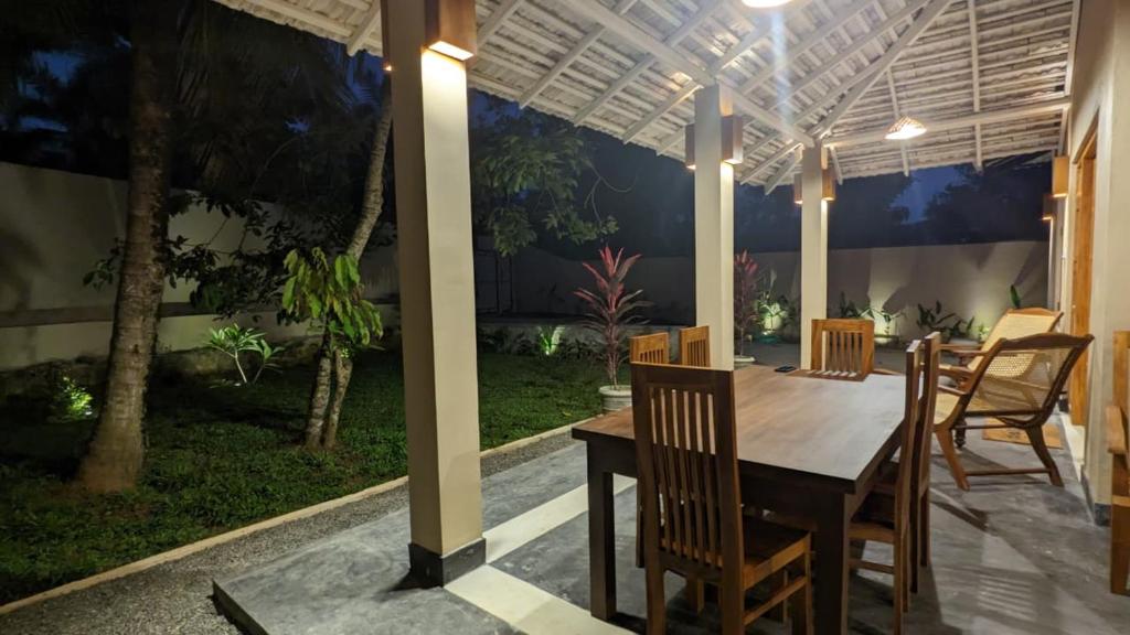 ein Esszimmer mit Tisch und Stühlen unter einer Pergola in der Unterkunft Bright house in Tangalle