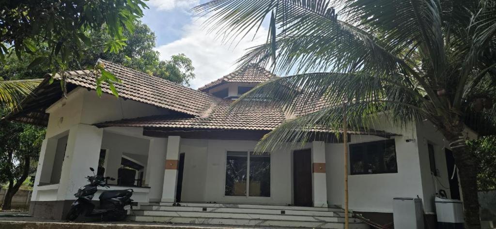 a house with a palm tree in front of it at BharathaPuzha Villa in Kārakkād