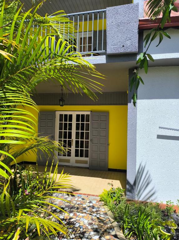 a house with a yellow front door and some plants at Location saisonnière Chez Paulette in Cilaos