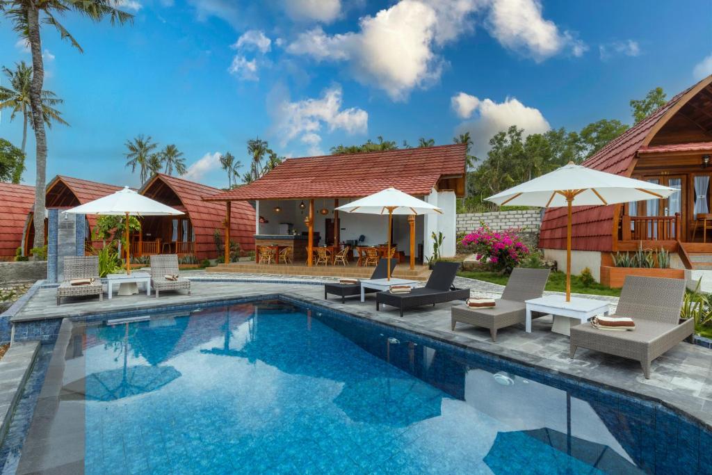 een zwembad met stoelen en parasols naast een huis bij Bunut Bungalow in Nusa Penida