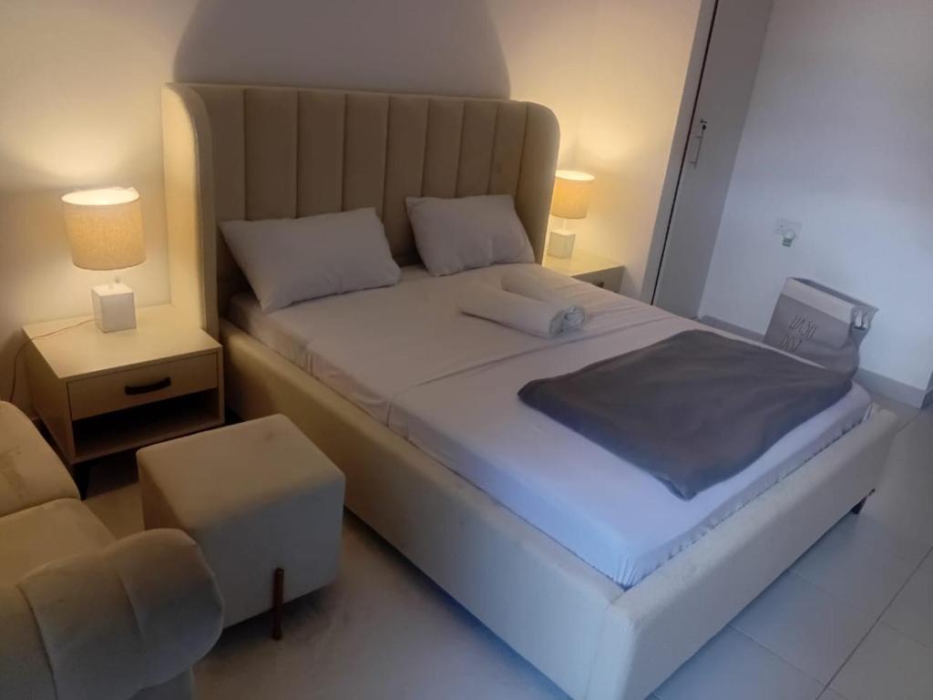 une chambre avec un grand lit blanc et une chaise dans l'établissement PONTOOn STUDIO, à Mombasa