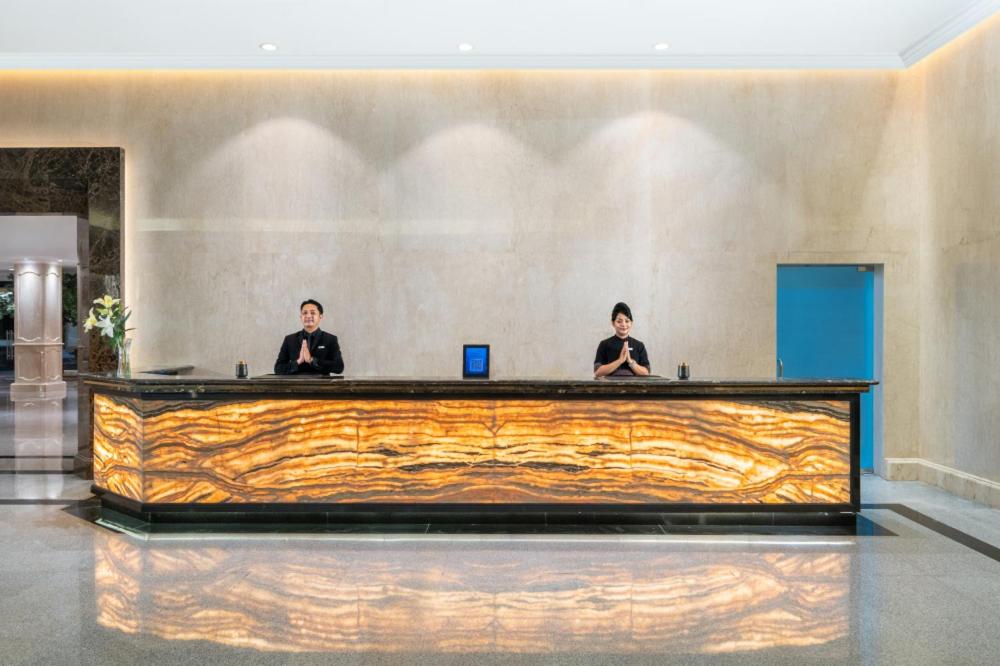 dos hombres sentados en un escritorio en el vestíbulo en Aston Cimone Hotel & Convention Center, en Kerontjong Satu